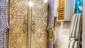 Une pièce dotée d’une grande porte en bois aux motifs complexes, d’un mur recouvert de carreaux et d’une échelle en bois.