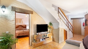 Een gezellige woonkamer met een televisie, een houten dressoir en een trap naar een hoger niveau.