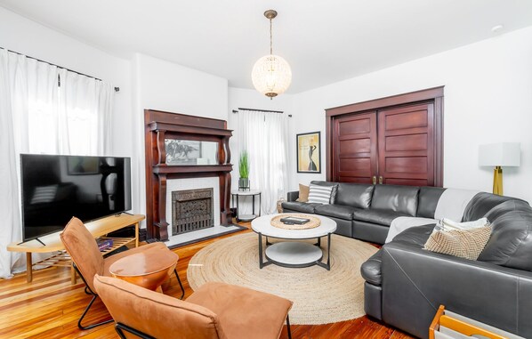Una sala de estar con chimenea, sofá de cuero, televisor y una mesa de centro.