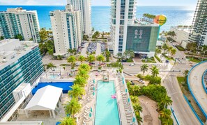 A hotel with a pool, palm trees, and a view of the ocean. - Luxury Condo with Stunning Views | Amazing Pools (Hollywood)