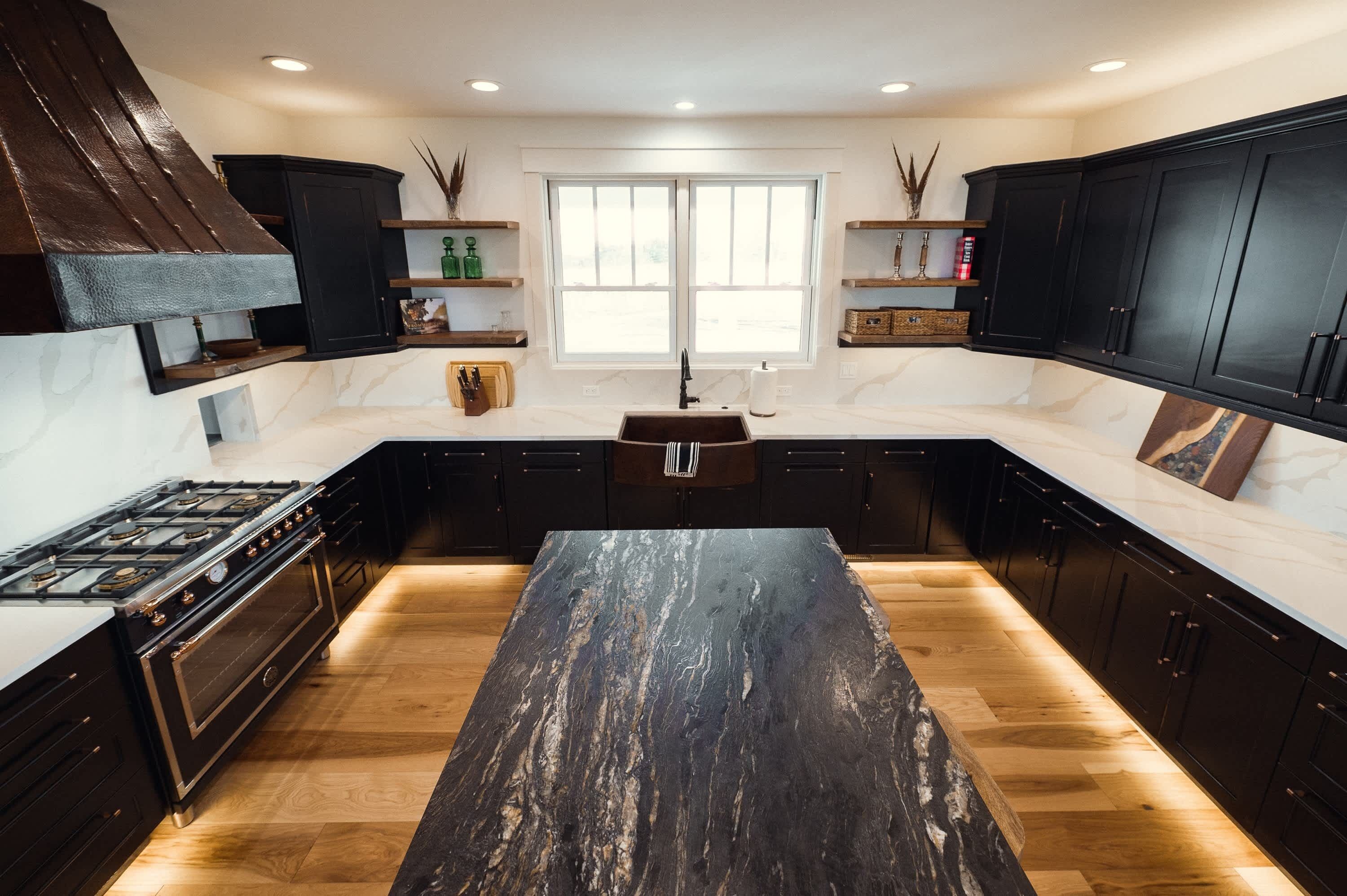 Une cuisine moderne avec des meubles de couleur sombre, un îlot central et une grande fenêtre.