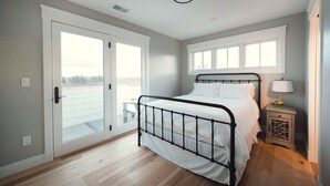 Une chambre à coucher avec un lit, une fenêtre, une porte et une table de chevet.