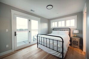 A bedroom with a bed, a window, a door, and a nightstand. - Ann Riley Farmhouse - Country Setting By The Horse Show (Williamsburg)