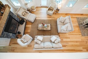 Ein geräumiges Wohnzimmer mit einem Steinkamin, einer großen Couch-Garnitur und einem Couchtisch mit dekorativen Accessoires.
