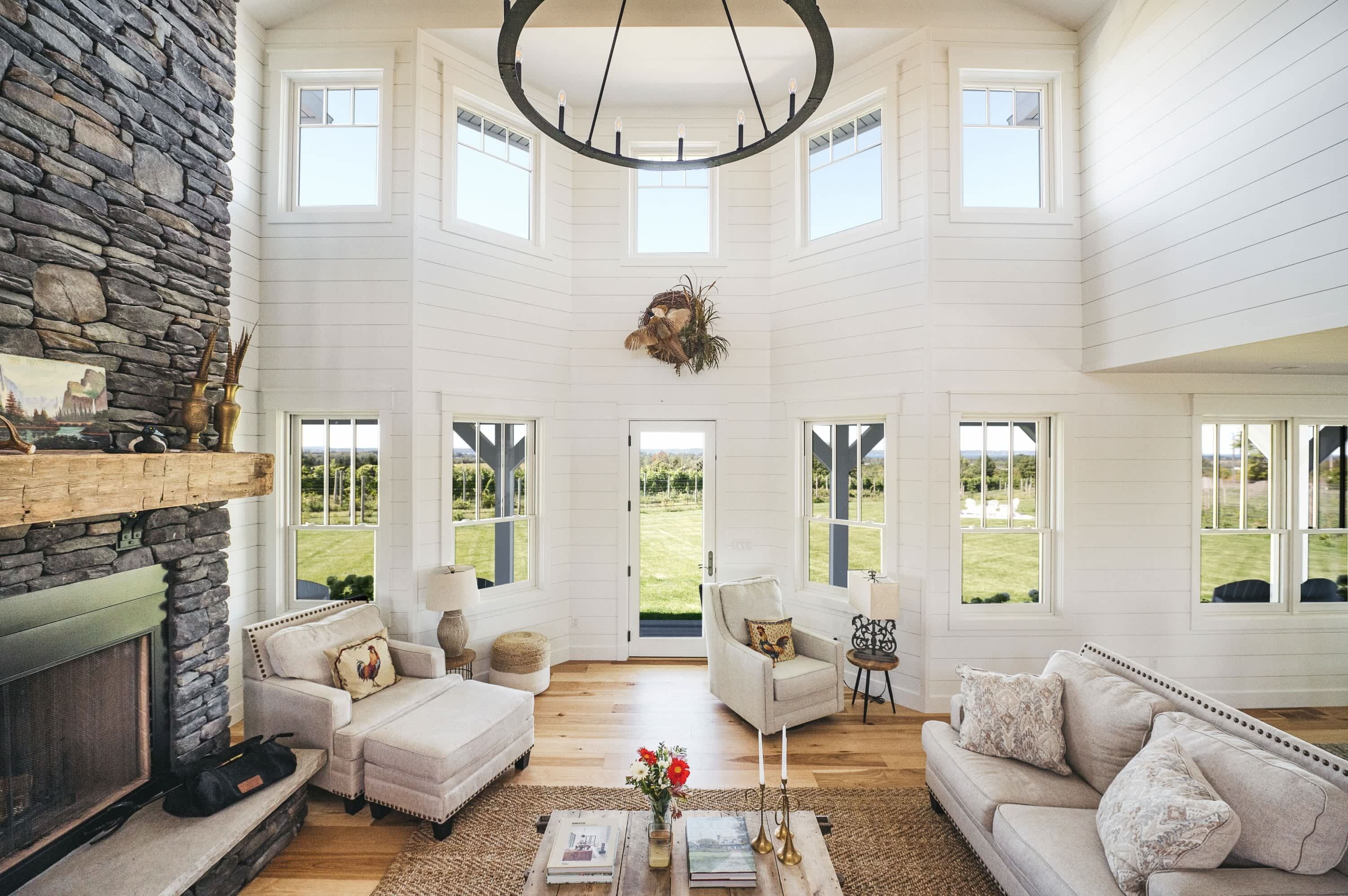 A spacious living room with a stone fireplace, multiple seating areas, and large windows offering views of the outdoors.