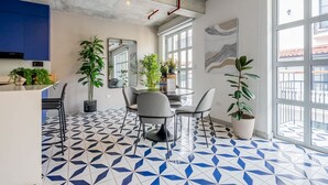 A modern kitchen with blue cabinets, a dining area with a round table and chairs, and large windows offering a view.