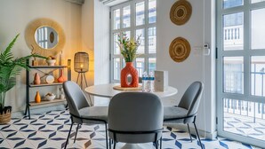 A modern dining area with a round table, two grey chairs, a decorative vase, and a potted plant. - w* | Extraordinary 2BR in Plaza Herrera (Panamá)