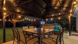 Un patio esterno con zona salotto coperta, un tavolo e sedie.