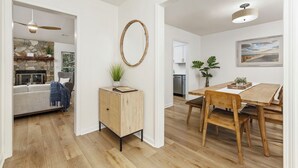 Un soggiorno moderno con camino in pietra, un tavolo da pranzo in legno con sedie e un grande specchio sulla parete.