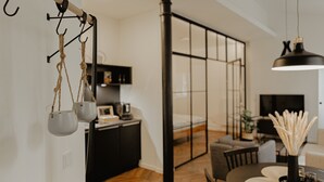 A modern living room with a dining area, a black metal column, and a hanging light fixture.