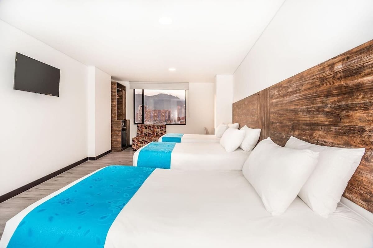 A hotel room with three beds, a wooden headboard, a flat-screen TV, and a city view.