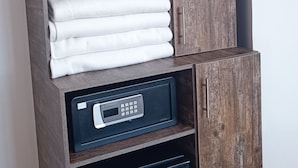 A wardrobe with a hanging space, a folded towel, and a black appliance below. - HOTEL AMERICAN VISA CORPORATE (Bogotá)