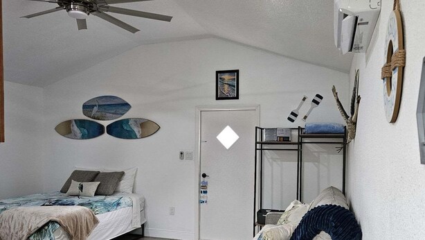 Une chambre à coucher avec un lit, une chaise, un ventilateur de plafond et une porte.