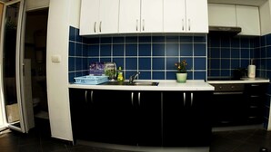 Una cocina con armarios blancos, salpicadero azul y un lavamanos.