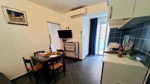 Una cocina compacta con comedor, un televisor de pantalla plana y un ventanal con cortinas.