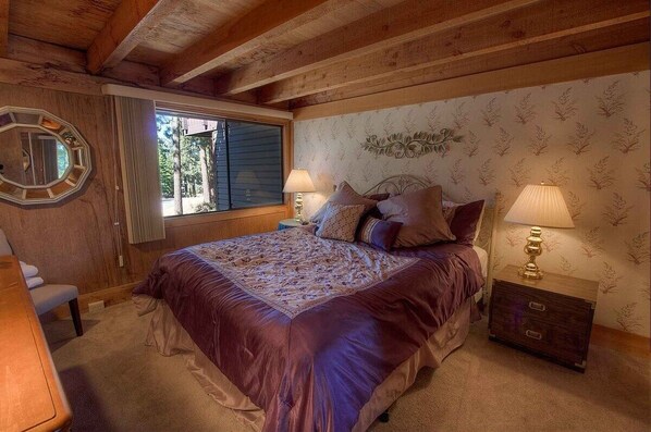 A bedroom with a large bed, two bedside tables with lamps, a wooden headboard, a window with blinds, and a mirror on the wall. - Chimney Rock Condo 3 Bedroom Condo by RedAwning (Zephyr Cove)