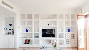 Un salon moderne avec un téléviseur à écran plat, des étagères blanches et des meubles bleus.