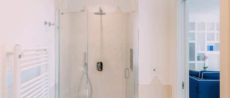 Une salle de bain moderne avec une douche à parois de verre, un porte-serviettes blanc et un meuble de salle de bain visible.