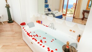 Une salle de bain moderne avec une grande baignoire, une statue et une vue sur la mer, visible à travers les portes coulissantes.