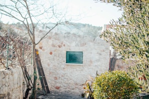 Un estrecho sendero de piedra que conduce a una rústica pared de piedra con una placa verde.
