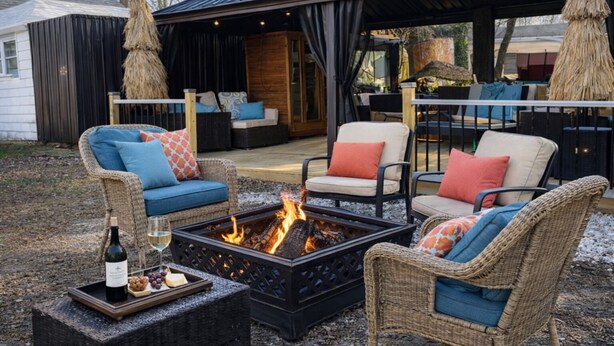 An outdoor seating area with wicker furniture, a fire pit, and a bottle of wine.