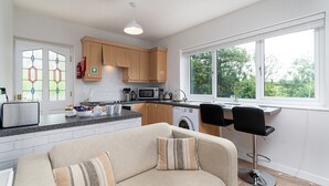 Une cuisine moderne avec des meubles en bois, un lave-linge encastré et un coin repas comprenant un canapé et des chaises.