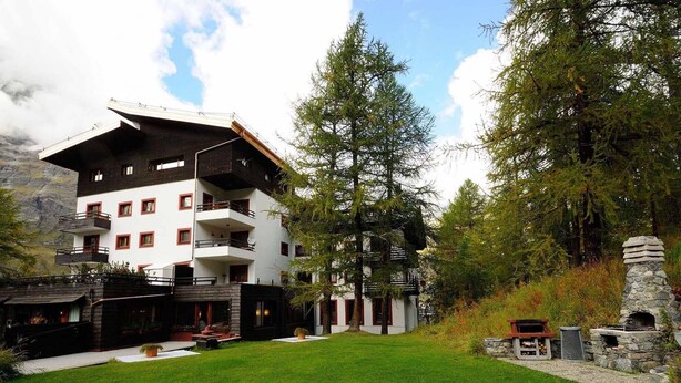 A multi-story building with balconies, surrounded by a well-maintained lawn and trees. - Residence Cervinia 3952 (Valtournenche)