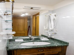 Une salle de bain avec un lavabo en marbre, un meuble en bois et un miroir.