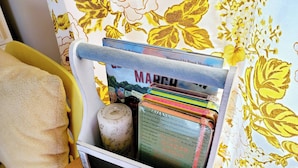 Uma mesa com um porta-revistas contendo uma revista de 'Março', um pequeno recipiente e uma toalha amarela.