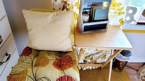 A small room with a bed, a wooden table, a bookshelf, and a patterned wall. - Room-cozy Yellow Queen Bed By Yale U (New Haven)