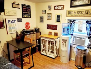 A kitchen area with a water dispenser, a coffee machine, and various signs on the wall. - Room-cozy Yellow Queen Bed By Yale U (New Haven)