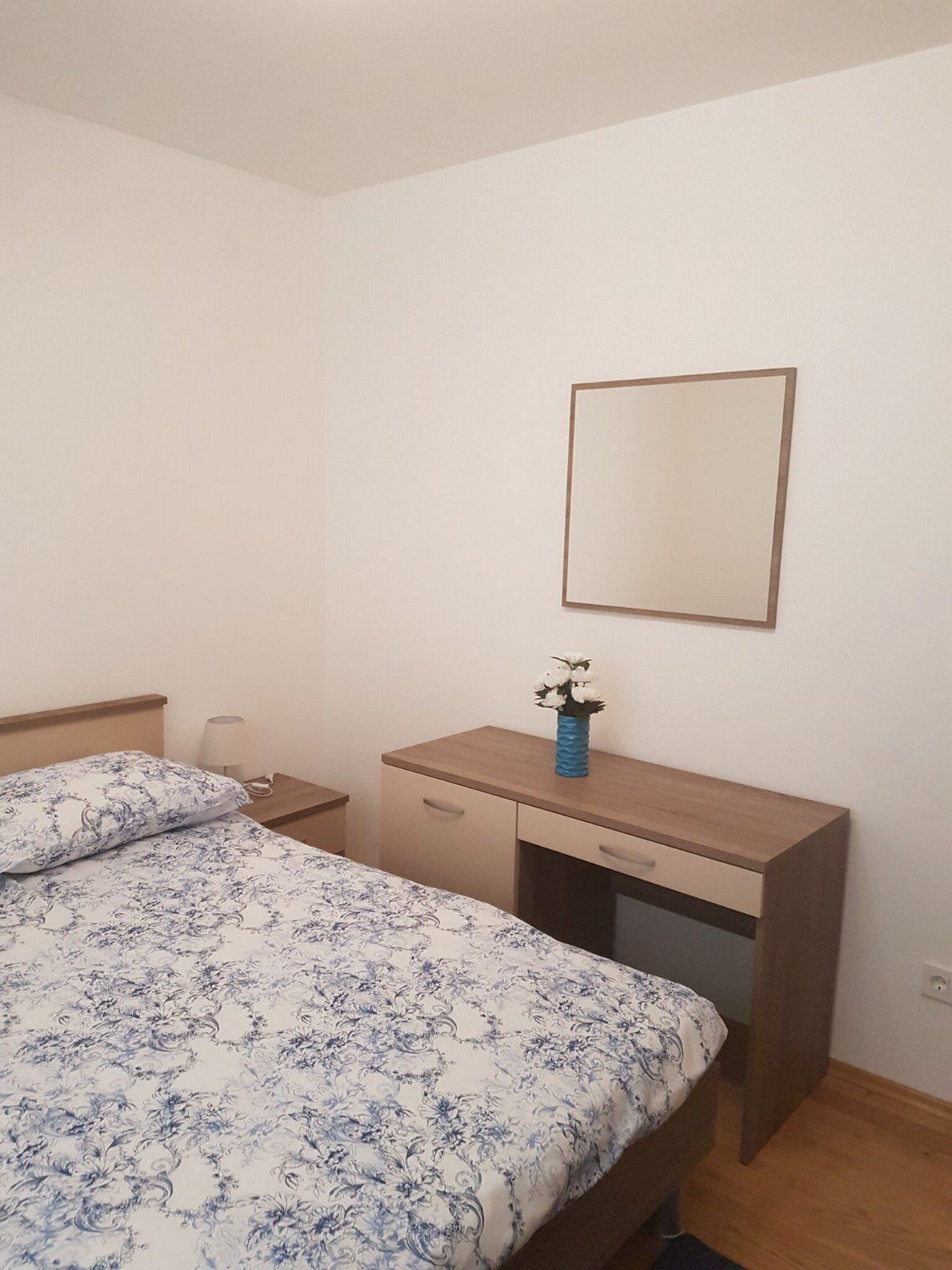 Ein Schlafzimmer mit einem Bett, einem Nachttisch, einer Kommode und einem Spiegel an der Wand.