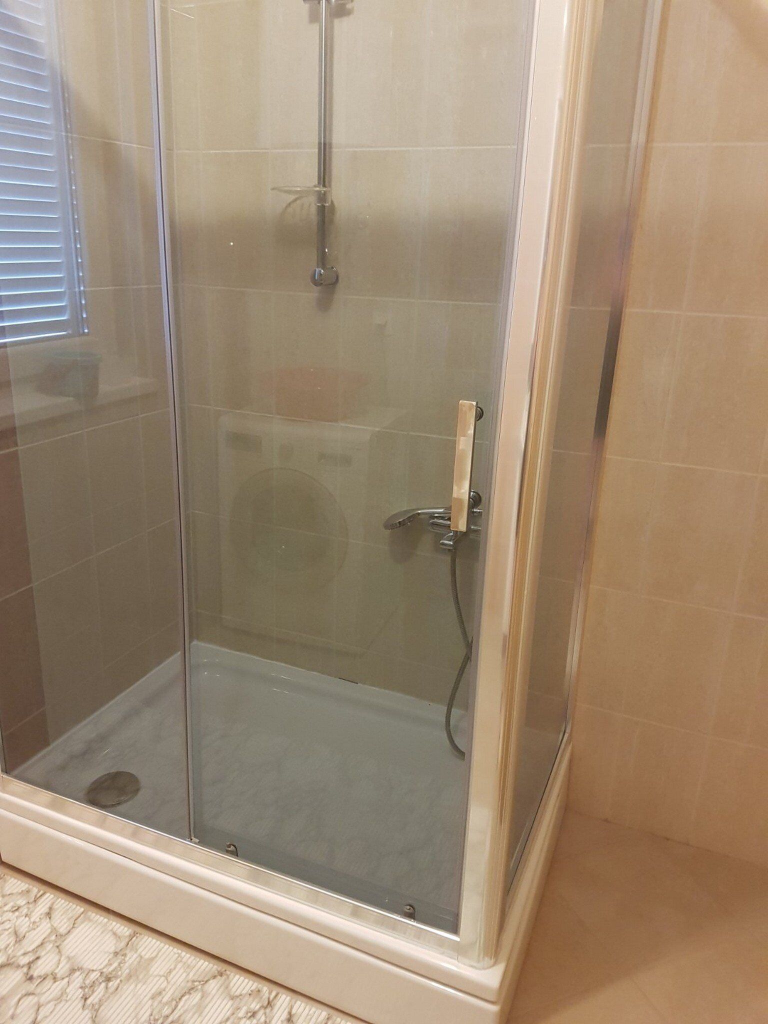 Une cabine de douche fermée par des parois en verre, équipée d’un pommeau de douche à main et d’un robinet à main.