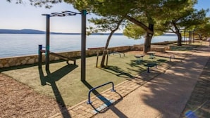 A park with exercise equipment, benches, and a view of the water. - Apartments Božić (Novi Vinodolski)