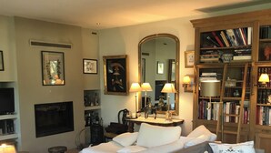 Ein Wohnzimmer mit einer Couch, einem Couchtisch, einem Fernseher, einem Kamin und einem Bücherregal.