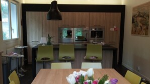 Ein moderner Essbereich mit einem Holztisch, gelben Stühlen und einer weißen Vase mit Blumen.