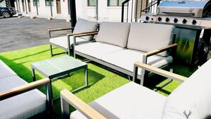 A patio area with a white sofa, two small tables, and a barbecue grill. - Modern Luxe King Suite Loft + Free Parking & Wifi (Memphis)