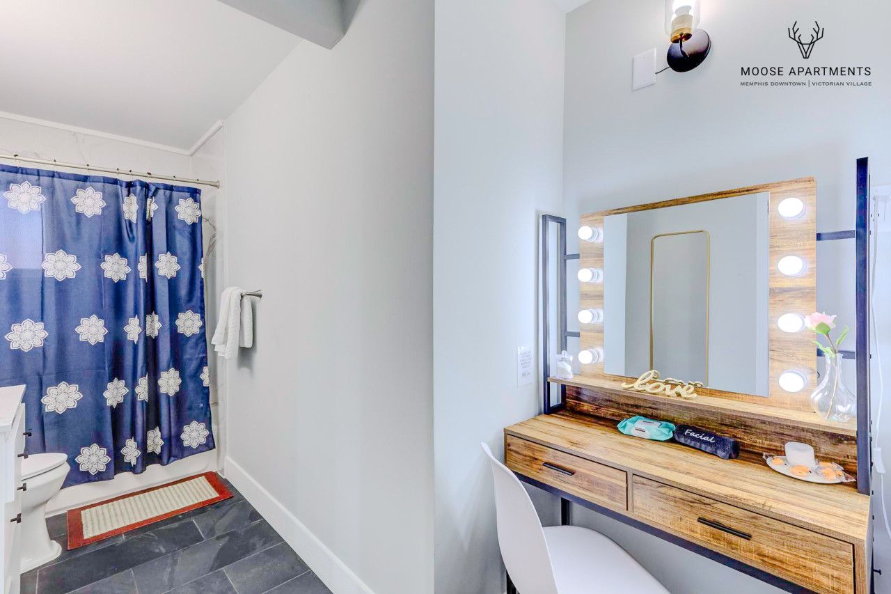 Een badkamer met douchegordijn, wastafel, spiegel en een bordje met de tekst Moose Apartments.