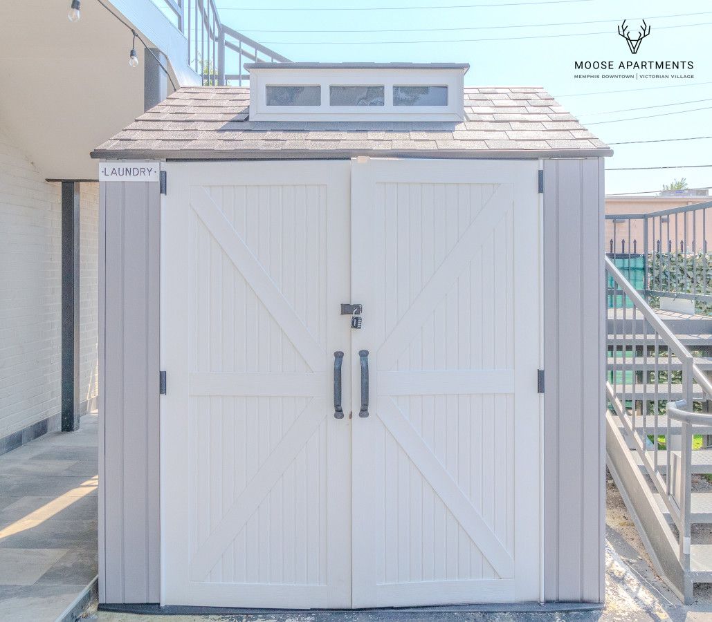 Una lavandería blanca con dos puertas y una pequeña ventana sobre la puerta.
