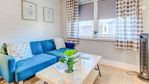 A cozy room with a blue sofa, a white coffee table, and a potted plant. - Modern Luxe King Suite Loft + Free Parking & Wifi (Memphis)