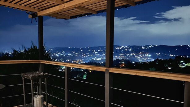Eine Dachterrasse mit einer Holz-Pergola, einem Whirlpool und Blick auf eine beleuchtete Stadtlandschaft bei Nacht.