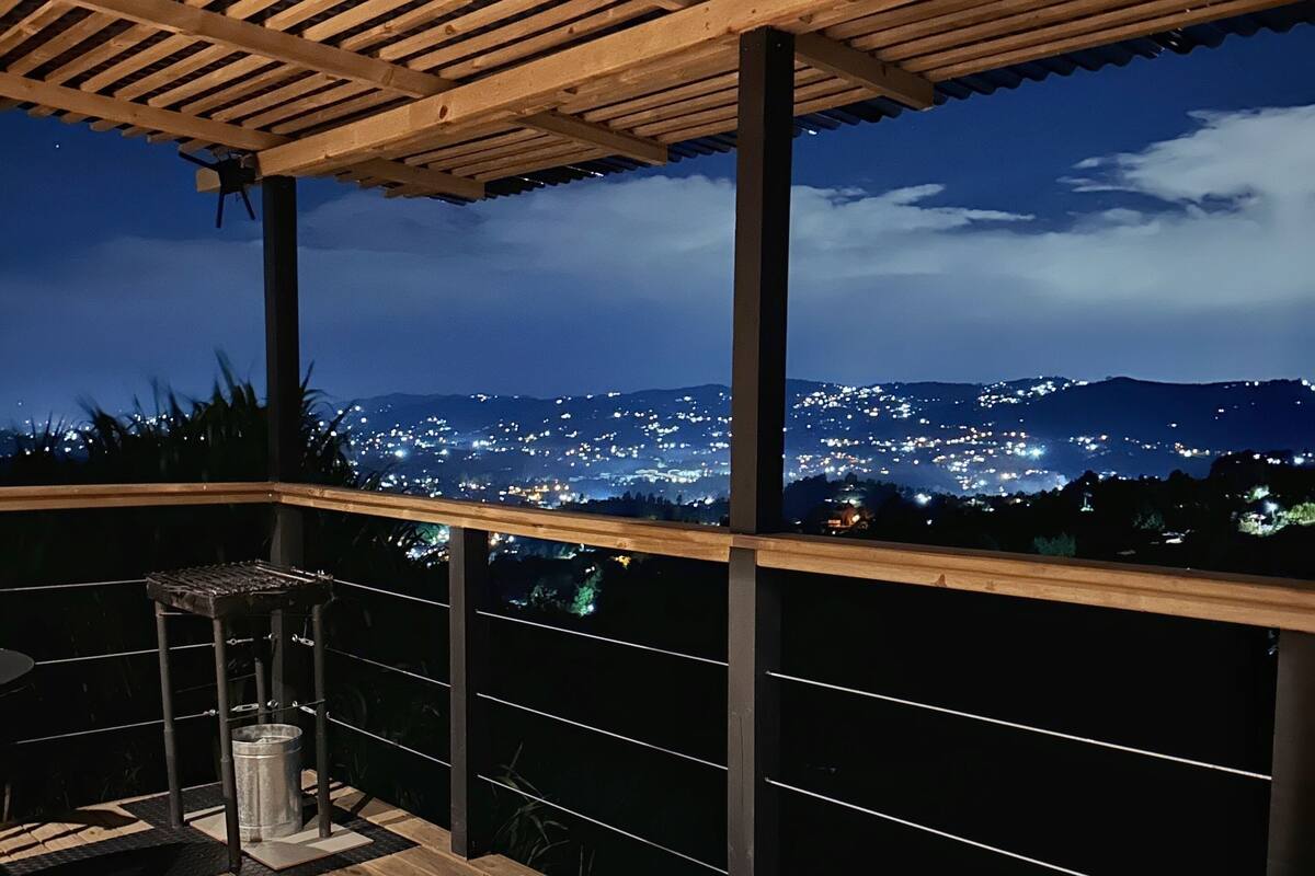 Eine Dachterrasse mit einer Holz-Pergola, einem Whirlpool und Blick auf eine beleuchtete Stadtlandschaft bei Nacht.