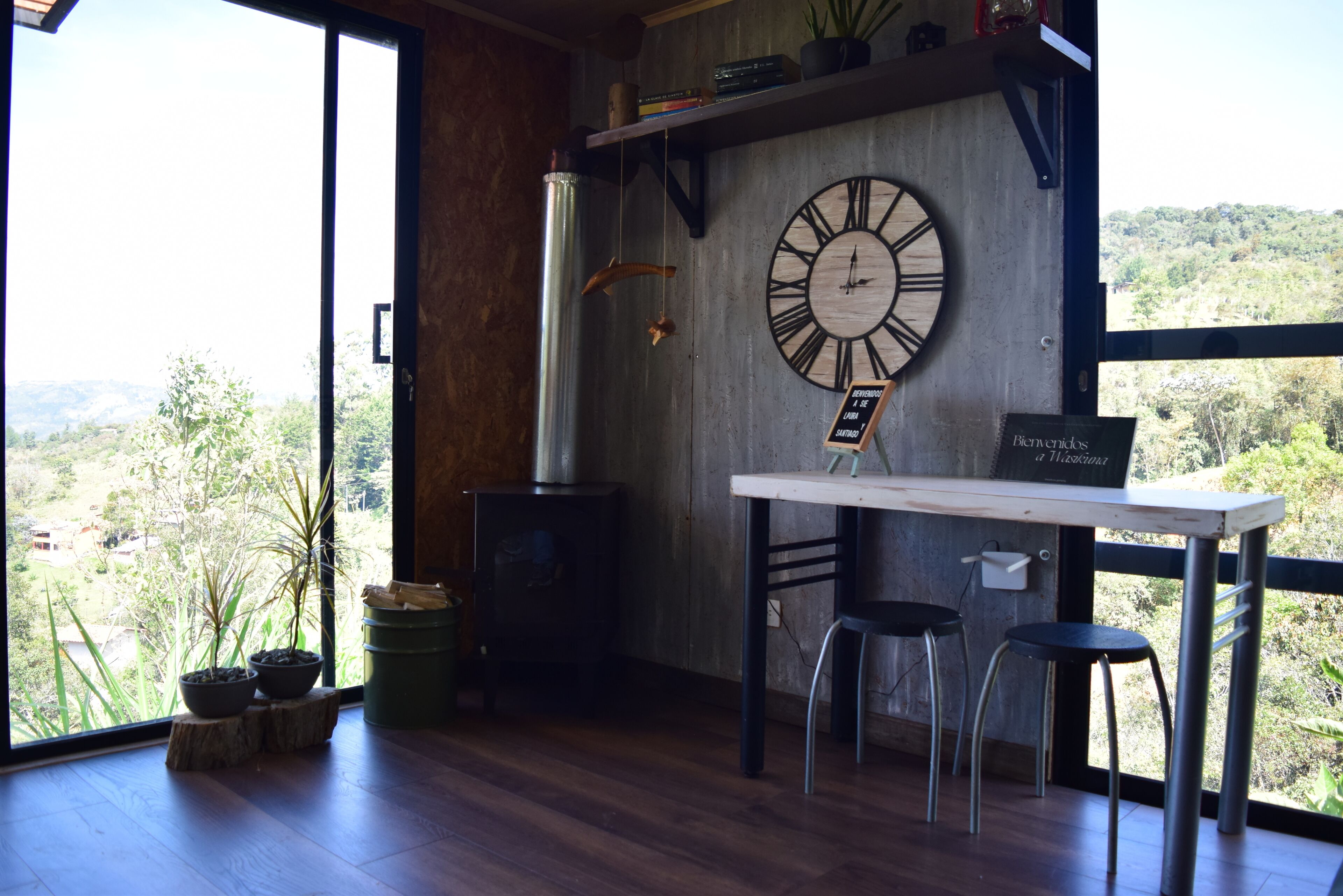Un interior rústico con un gran reloj de pared, pisos de madera y vistas al exterior.