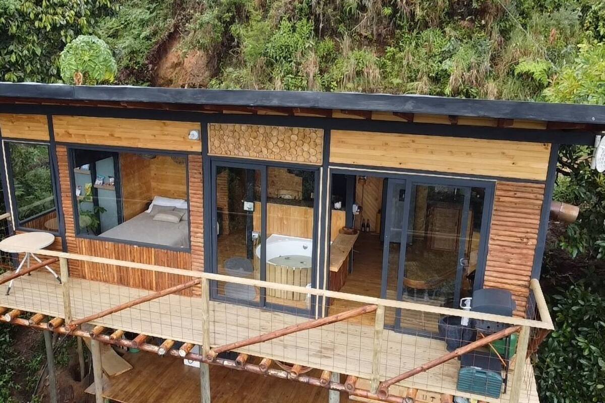 Eine moderne Holz-Blockhütte mit Balkon, großen Fenstern und einem Whirlpool.