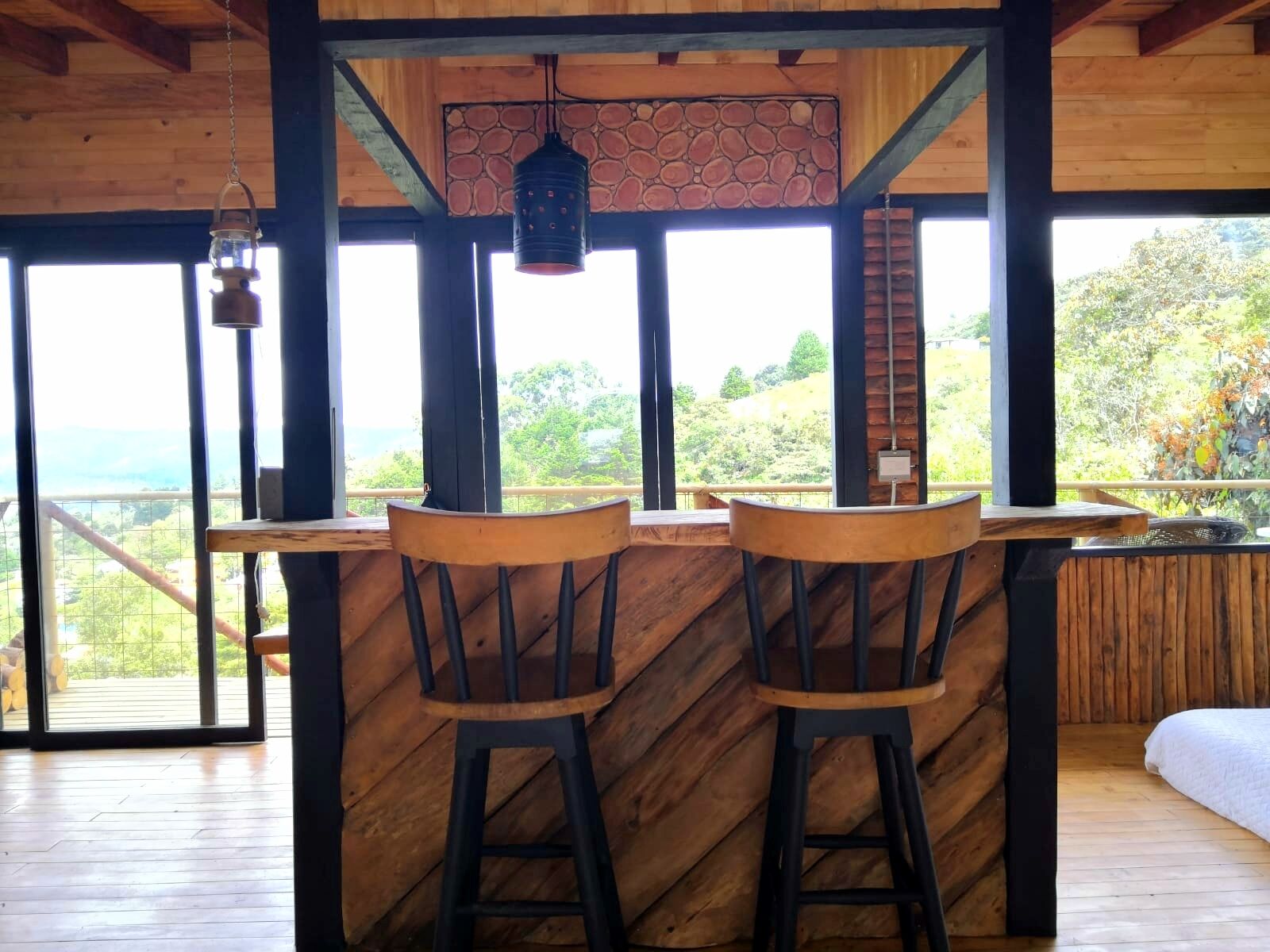 A wooden bar area with two stools and a hanging lantern.