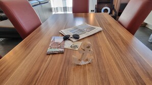 Una mesa de madera para comer con un periódico, gafas de sol y un folleto de CityPlan.