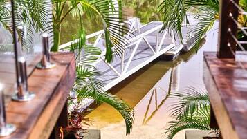 A bridge over a water feature with palm trees and a wooden deck.