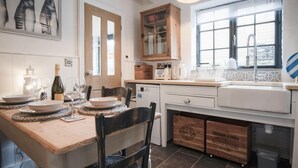 Een keuken met een houten eettafel, een raam met uitzicht en een kast met glazen deuren.