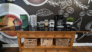 Een koffiebar toonbank met een rustiek houten ontwerp, met een koffieapparaat, potten en een decoratieve wand met illustraties over koffie.