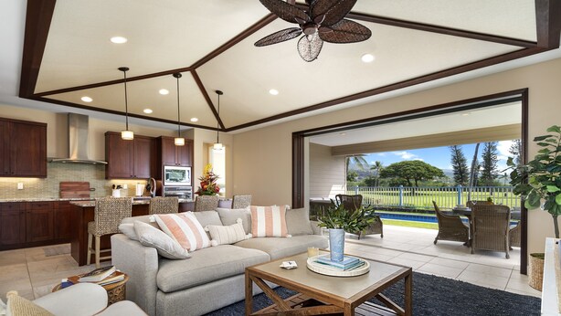 A spacious living area with a sofa, coffee table, and dining table. There is a kitchen with wooden cabinets and a large window overlooking a garden. - Holua Kai#8  w/ Private Pool, Ocean & Golf Views, Community Pool & Spa (Kailua-Kona)